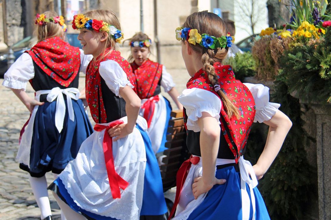 Tanzende Mädchen in sorbischen Trachten mit Blumenkränzen im Haar