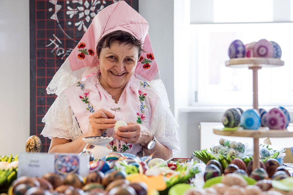 Frau in sorbischer Tracht verziert ein Osterei 